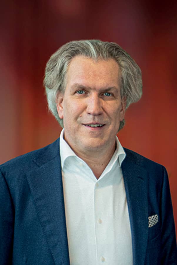 Portrait d'un homme d'affaires d'environ 50 ans, cheveux gris, costume bleu, sur fond dégradé orange
