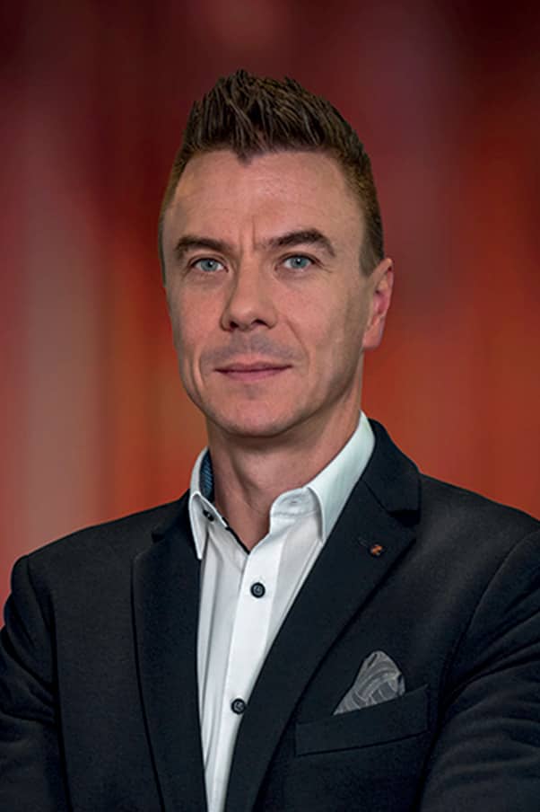 Portrait d’un homme d’affaires en costume sombre et chemise blanche avec pochette, sur fond rouge dégradé